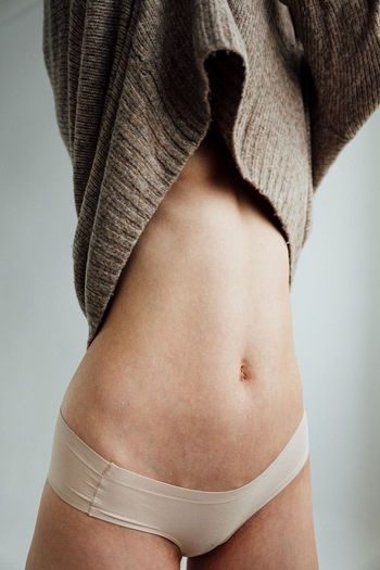 Midsection of woman standing against gray background