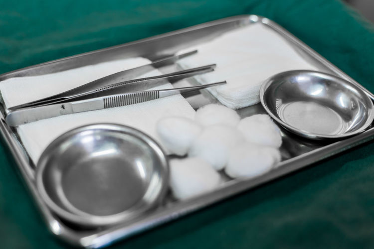 High angle view of cotton balls and equipment with bowls in tray on table in hospital