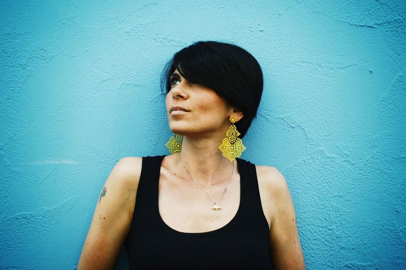 Thoughtful mid adult woman looking away against blue wall