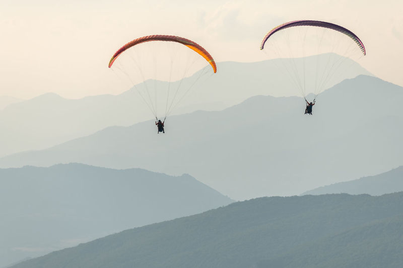 People paragliding against mountain range