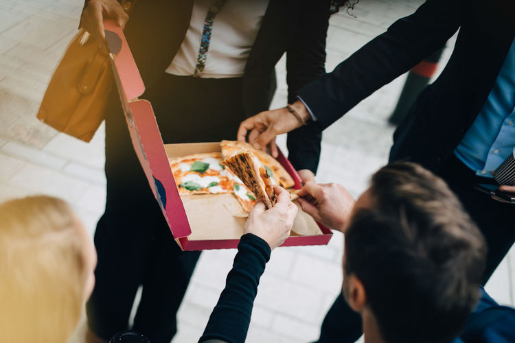 High angle view of business colleagues are eating pizza from box in city