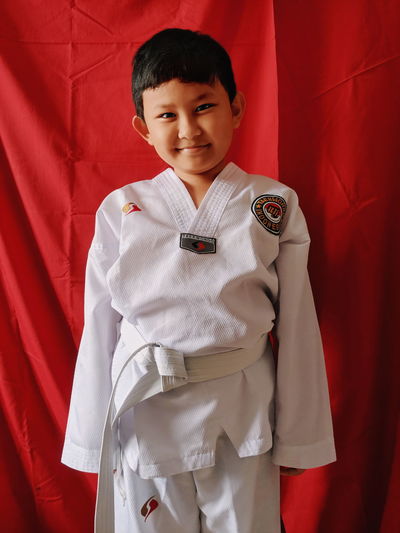 Portrait of smiling boy standing against red curtain