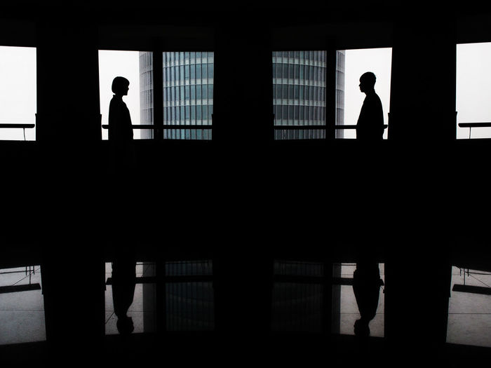 Silhouette man standing in front of window