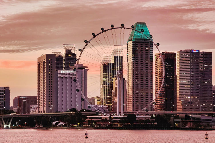 Modern buildings by river against sky in city