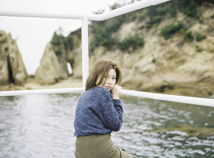 Woman sitting on pier over river