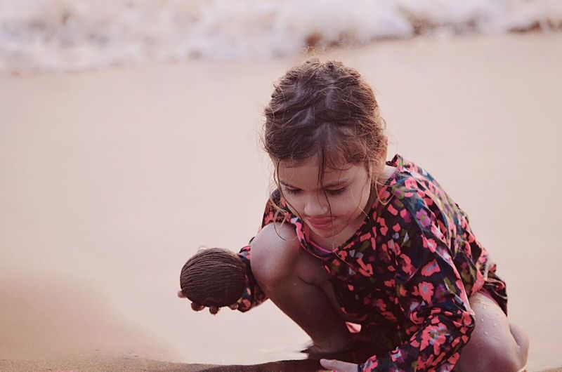 Close-up of wet girl playing with sand on shore at beach