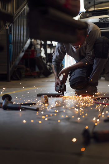 Repairman cutting metal on floor in auto workshop