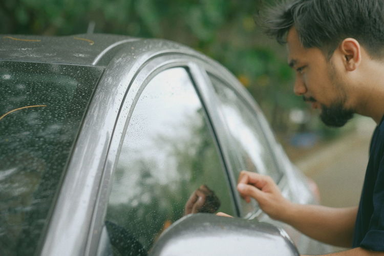 A man knock a car window after the rain