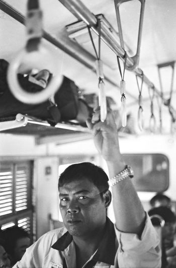 Portrait of man holding handle while standing in train