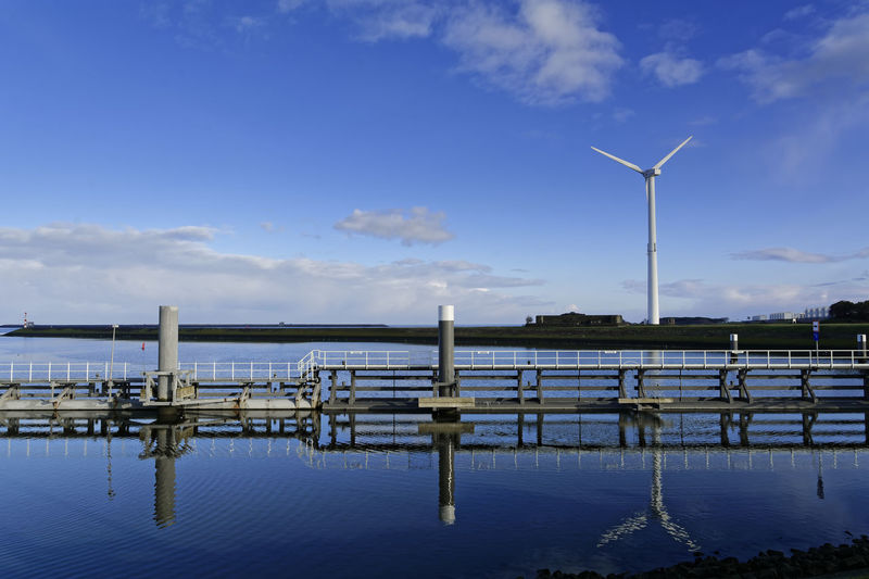 Wind turbines in sea against blue sky