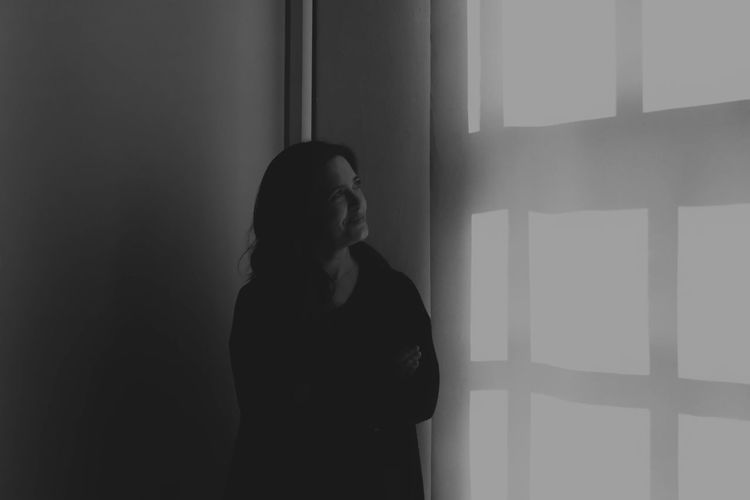 Thoughtful woman with arms crossed looking at wall