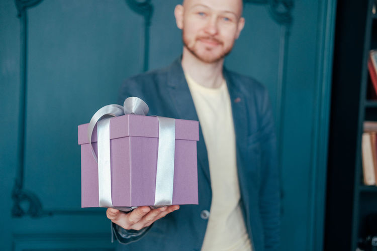 Handsome man giving gift at home