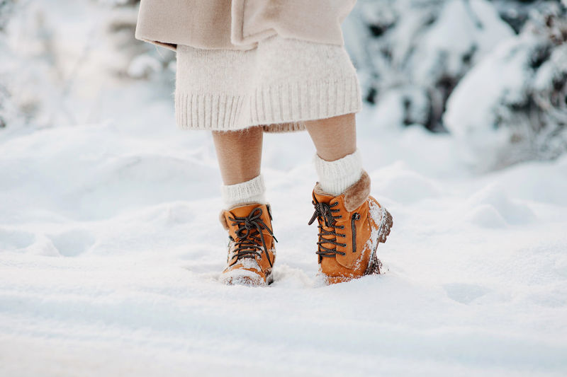 Warm winter boots in the snow. a girl in a beige faux fur coat walks through a snowy forest. fashion