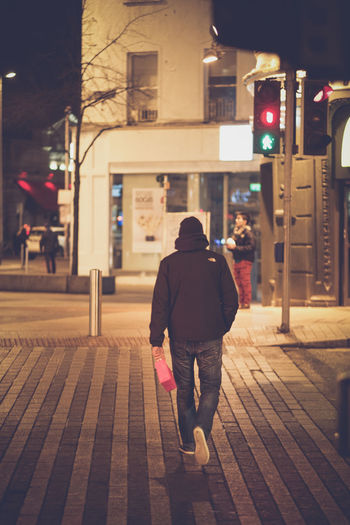 Full length of woman standing on illuminated city street at night