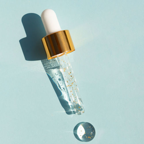 Close-up pipette with a hyaluronic moisturizing 24k gold serum on a blue background. beauty skin car