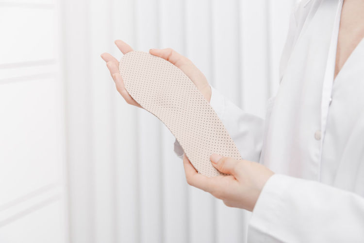 Midsection of doctor holding insoles