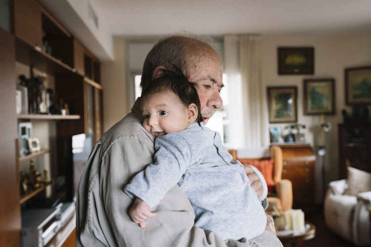 Great-grandfather holding baby at home
