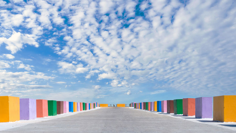 The cement bridge extends into the sea. with colorful barrier panels in the blue sky