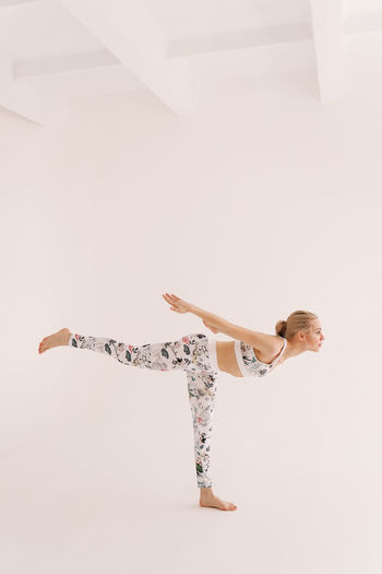 Full length of young woman jumping on white background