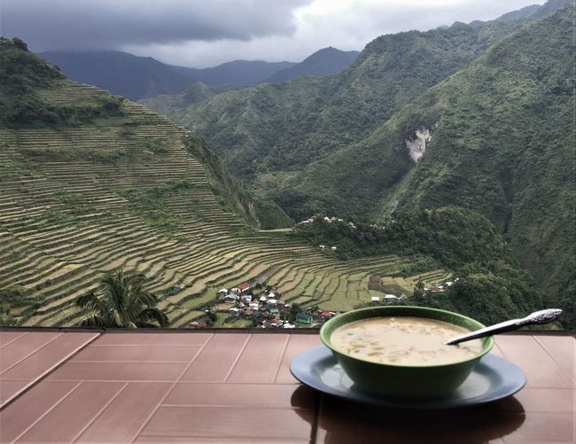 High angle view of soup on table against mountains with rice fields 