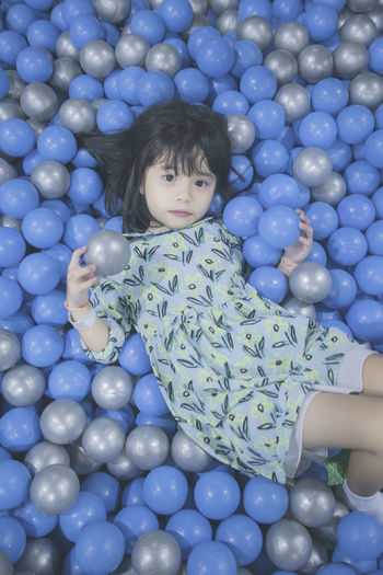 Portrait of innocent girl lying down in ball pool