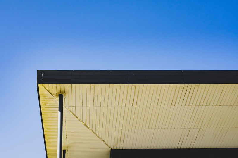 Low angle view of yellow building against clear blue sky