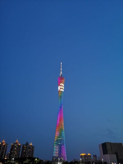 Low angle view of illuminated tower against clear blue sky