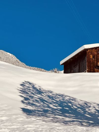 Snow covered alpine land and houses against clear blue sky