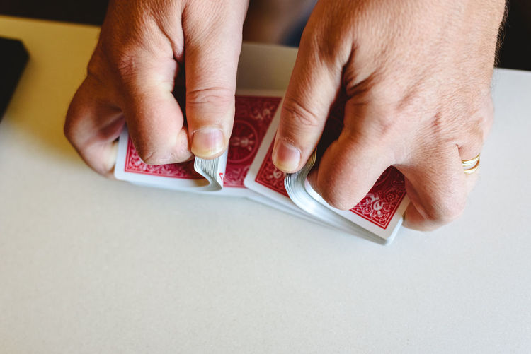 Cropped hands of person holding playing cards on table