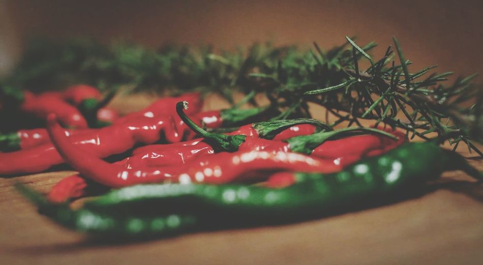 Close-up of chili peppers by rosemary on table