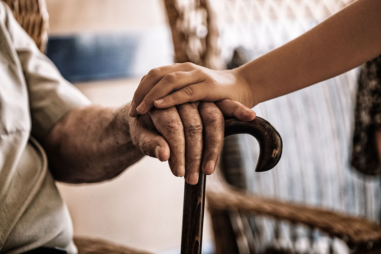Midsection of man touching grandfather hand