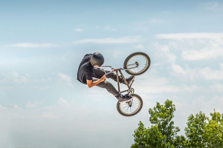 Low angle view of man performing stunt on bicycle against sky