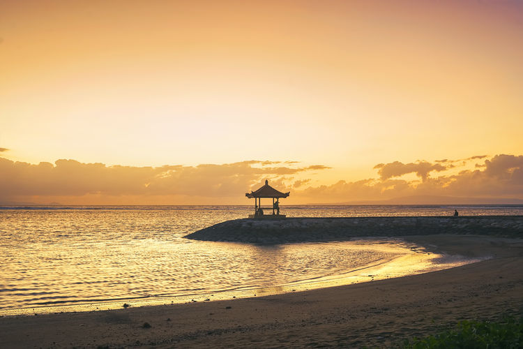 Silhouette beach against sky during sunset