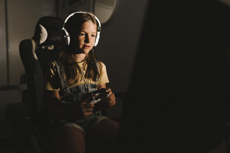 Girl playing video game at home during night