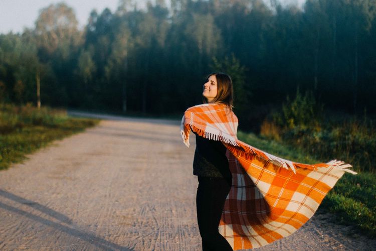 Young woman with blanket standing on road