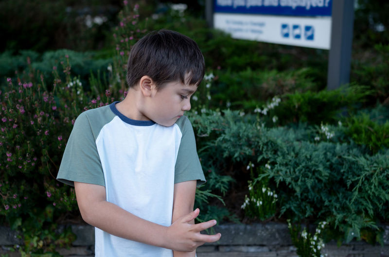 Boy looking away while standing against plants