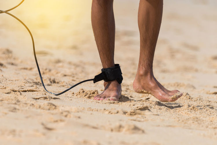 Low section of man wearing cable at beach