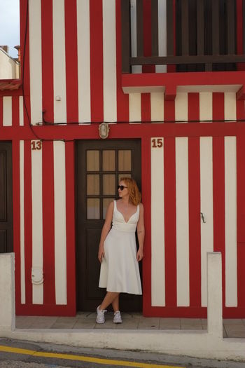 Full length of woman standing against red wall