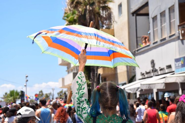 Rear view of girl holding umbrella in crowd during gay pride parade