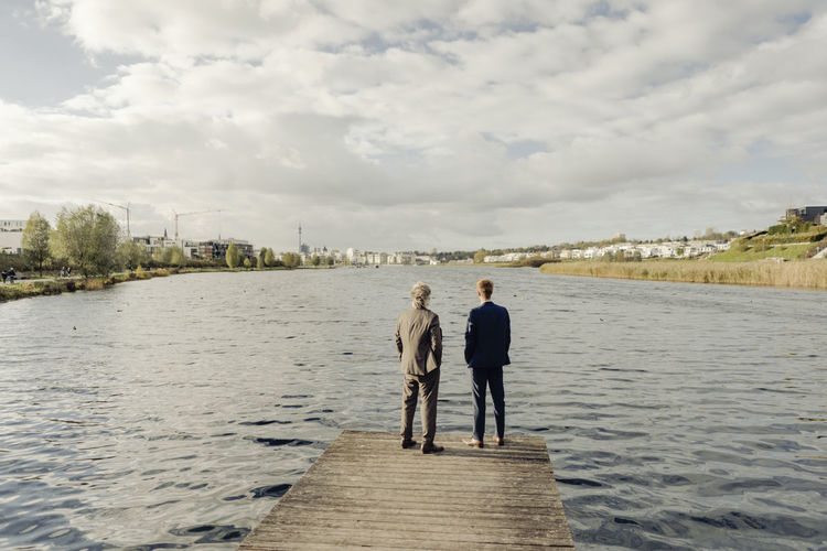 Two businessmen standing on jetty at a lake