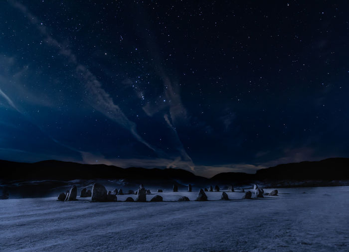 Scenic view of a stone-circle in a field at night under a starry sky. 