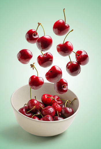 Cherries flying on green background