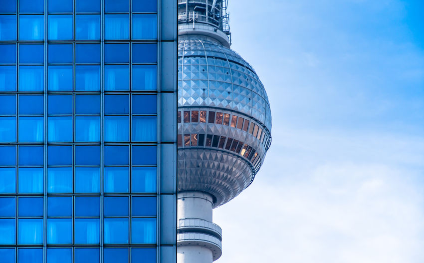 Low angle view of fernsehturm by building against sky