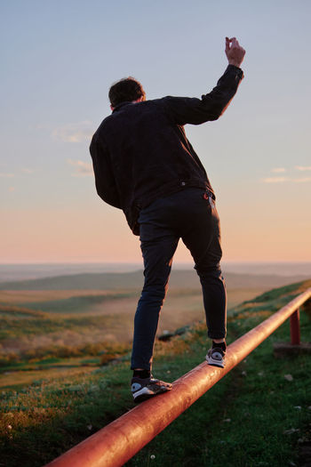 Low section of man standing on pier against sky during sunset