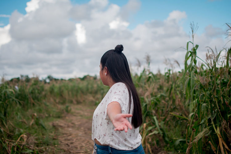 Woman standing on field against cloudy sky