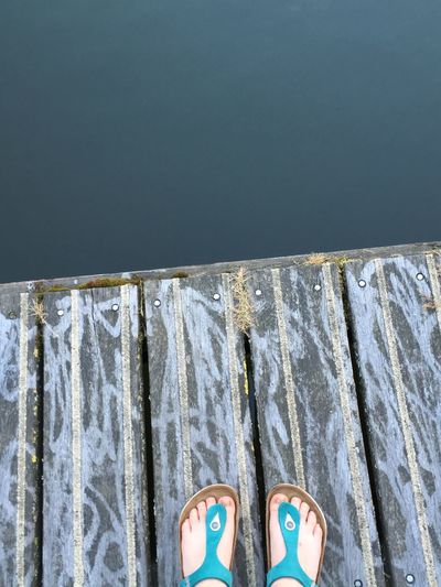 Low section of woman standing on pier over lake