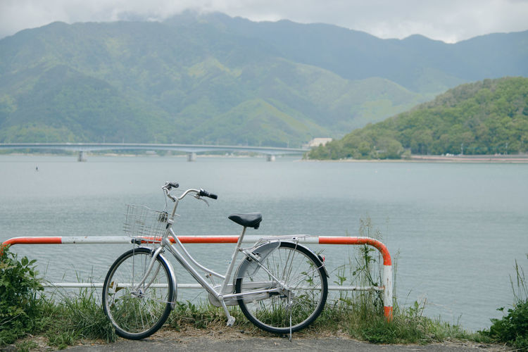 Bicycle by river against mountains