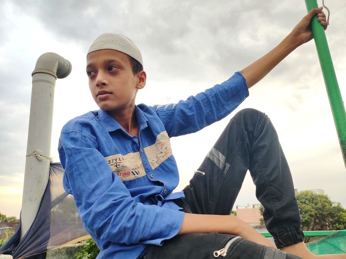 Portrait of young man looking away against sky