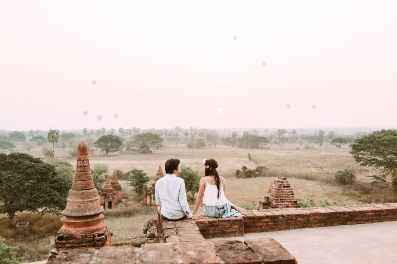 Rear view of couple sitting on temple against sky