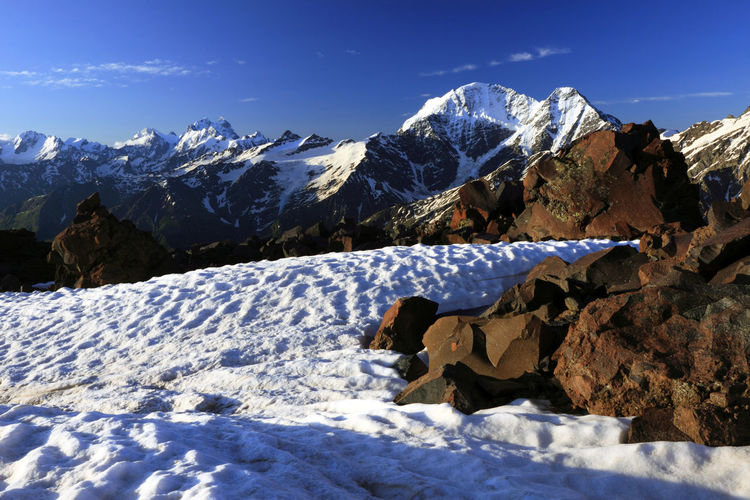 Scenic view of snow covered mountains against blue sky